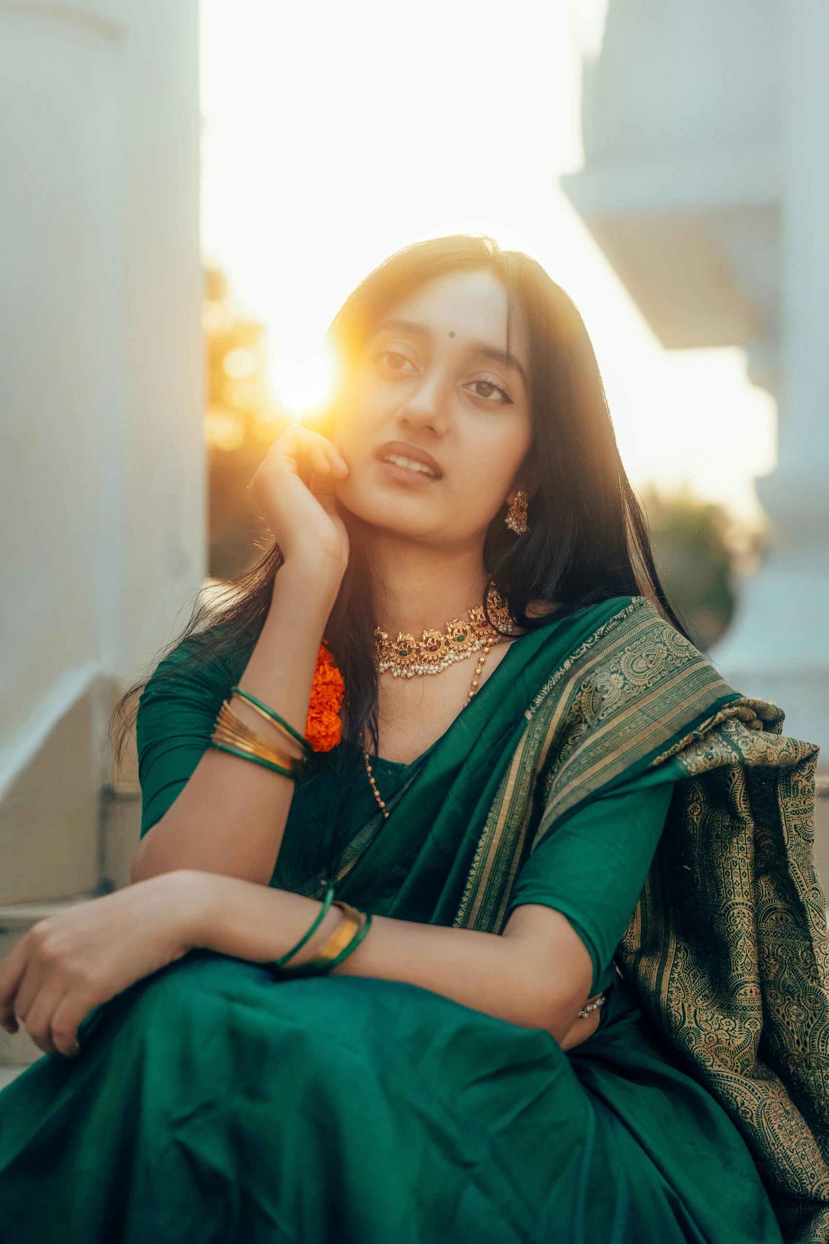 Stunning portrait of a young woman wearing a green saree, capturing a serene and artistic moment at sunset.